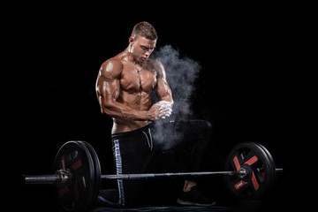 Fototapeta na wymiar Photo of strong muscular bodybuilder athletic man pumping up muscles with barbell on black background. Workout energy bodybuilding concept.