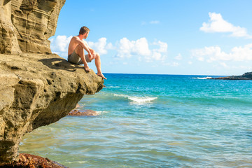 Tourist sit on rock of the beautiful Green Sand Beach, Big Island, Hawaii
