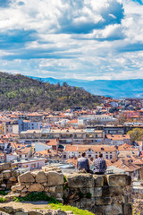 Rear view of two unrecognizable boys sitting on a stone wall at Nebet Tepe overlooking the city of Plovdiv, Bulgaria