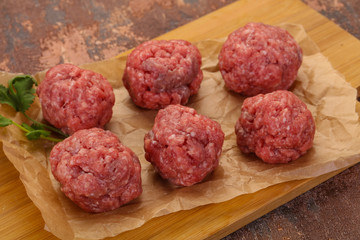 Raw meatball over wooden background