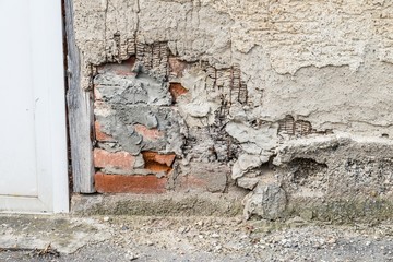 Eine beschädigte Hausmauer und abgeplatzter Außenputz mit einem großen Loch, Deutschland
