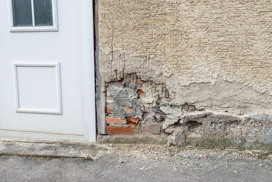 Eine besch&auml;digte Hausmauer und abgeplatzter Au&szlig;enputz mit einem gro&szlig;en Loch, Deutschland
