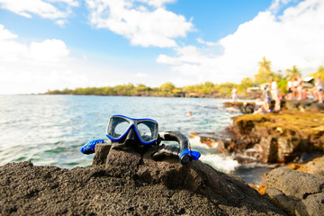 A Colorful snorkle or diving mask located on the rocks with snorkling group on the back