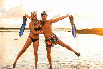 Couple is going to swim and snorkle on hawaii beach at the sunset