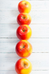 apple fruits in a row, white wooden table background