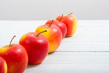 apple fruits in a row, white wooden table background