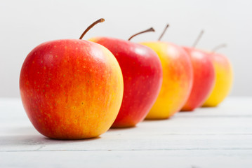 apple fruits in a row, white wooden table background