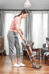 Asian girl cleaning her hair at home with a wireless vacuum cleaner