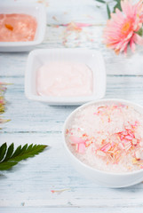 beauty product samples, cosmetic cream, bath salt, liquid soap and pink flower, white wood table