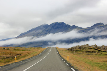 Road with clouds and mountains in background (Iceland)