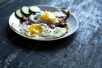 plate of fried eggs with vegetables on a dark background