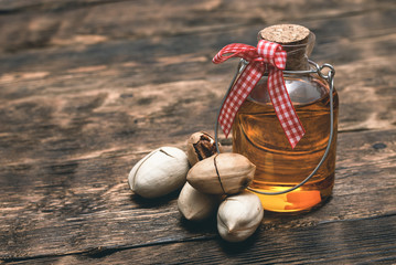 Pecan nut oil in a bottle on brown wooden table background.