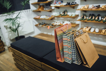 Gift bags on racks on the background of shelves with shoes in the shop