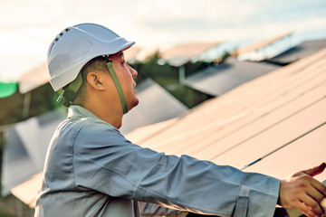 Asian professional engineer inspecting mountain solar photovoltaic panels in the sunset