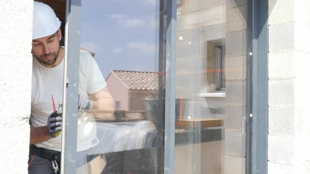 handsome young man installing bay window in a new house construction site