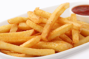 Portion of freshly made pommes frites or French fried potato chips in a white dish with red sauce isolated on white viewed high angle close up for advertising.