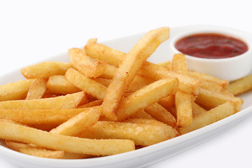 Portion of freshly made pommes frites or French fried potato chips in a white dish with red sauce isolated on white viewed high angle close up for advertising.