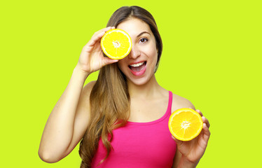 Pretty charming joyful attractive cheerful funny positive natural girl having two pieces of orange hide one eye isolated on yellow background with copy space for advertisement