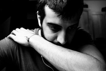 Young man depressed with headphones. Concept of sadness and loneliness. The difficulties of being young. Portrait in black and white