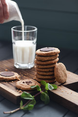Vegetarian sweets for healthy sugar free breakfast. Peanut butter and almond cookies with chocolate drops served with plant milk in glass and mint on dark oak board