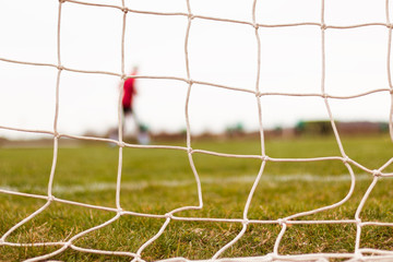 Football goal net and a player warming up