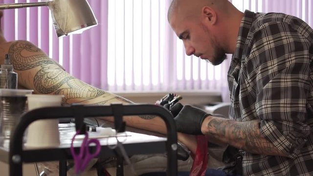 A tattoo master makes a tattoo to a client.