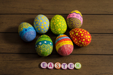 Easter made from colorful letters and colorful decorated easter eggs on wooden background
