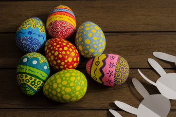 Colorful decorated easter eggs an bunny paper chain on wooden background