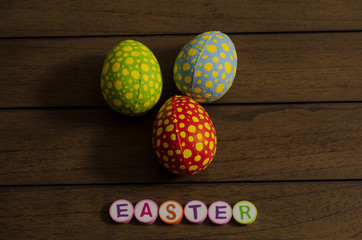 Easter made from colorful letters and colorful decorated easter eggs on wooden background
