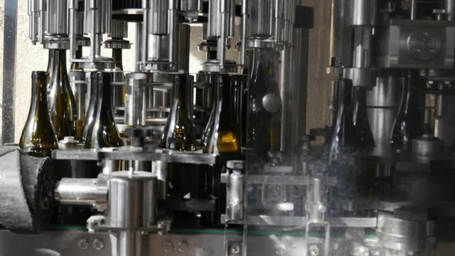 young man wine maker working filling wine bottle with automatic bottling machine