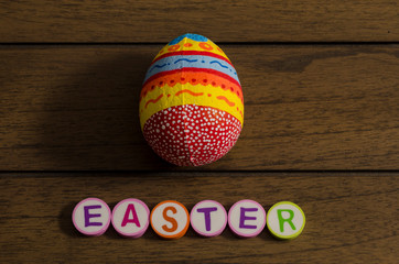 Easter made from colorful letters and colorful decorated easter egg on wooden background