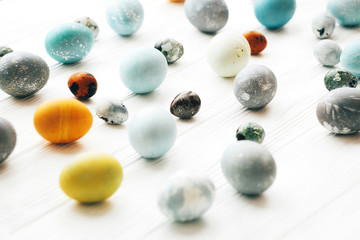Happy Easter greeting card. Stylish Easter eggs on white wooden background. Modern easter eggs painted with natural dye in yellow,blue,green,grey marble colors.