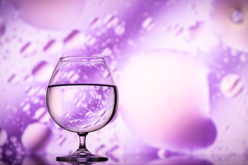 transparent glasses with water with oily drops on colorful background 