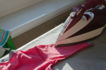 Iron and clothes on a table in home