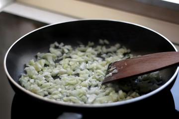Frying onion on a pan with olive oil. Selective focus.