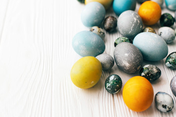 Fototapeta na wymiar Stylish Easter eggs border on white wooden background, copy space. Modern easter eggs painted with natural dye in yellow,blue,green,grey colors. Happy Easter greeting card