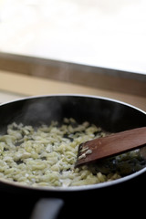 Frying onion on a pan with olive oil. Selective focus.