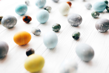 Happy Easter greeting card. Stylish Easter eggs on white wooden background. Modern easter eggs painted with natural dye in yellow,blue,green,grey marble colors.
