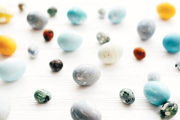 Happy Easter greeting card. Stylish Easter eggs on white wooden background. Modern easter eggs painted with natural dye in yellow,blue,green,grey marble colors.