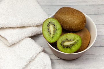 Kiwi slices on a wooden table next to a white towel