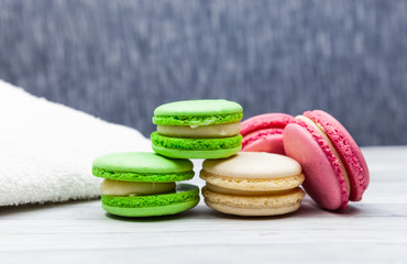 Assorted colorful macaroons on blue background, next to white towel