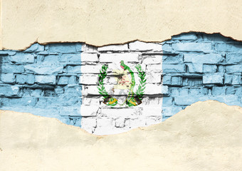 National flag of Guatemala on a brick background. Brick wall with partially destroyed plaster, background or texture.