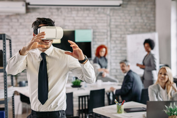 Businessman having fun while wearing virtual reality glasses in the office.