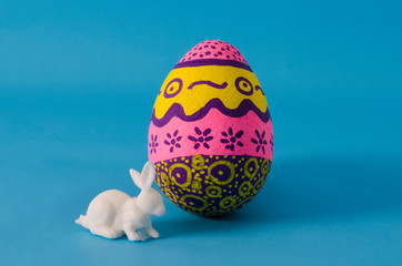 Colorful egg decorated and white bunny on blue background. Decoration for Easter Day