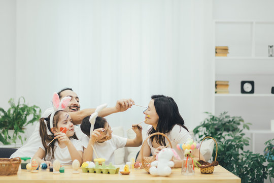 Father and two cute little children decided to colour their mother's face. Sister and brother wearing bunny ears. Relaxed atmosphere.