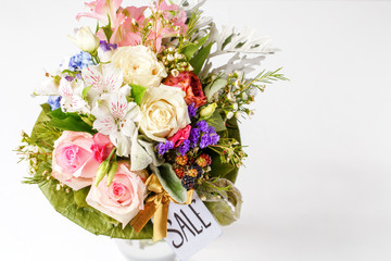 Image from above of romantic bouquet of pink roses, lilies, green leaves with postcard