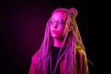 beautiful girl in the light of neon colored lamps light yellow purple wearing glasses on black background
