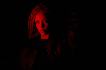 beautiful girl in the light of neon colored lamps light red on black background