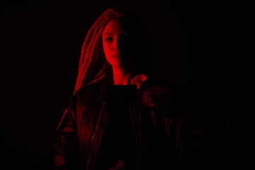 Naklejka premium beautiful girl in the light of neon colored lamps light red on black background