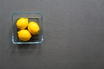 Top view on the table set with yellow lemons and grey tablecloth